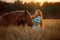 Beautiful  young woman with red tinker horse in oats field