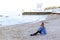 Beautiful young woman relaxes sitting on beach and enjoys view o