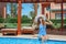 Beautiful young woman at the resort sits on the edge of the pool