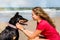 beautiful young woman sharing a tender moment with her dog on the beach