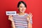 Beautiful young woman with short hair holding welcome paper doing ok sign with fingers, smiling friendly gesturing excellent