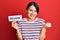 Beautiful young woman with short hair holding welcome paper screaming proud, celebrating victory and success very excited with