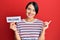 Beautiful young woman with short hair holding welcome paper smiling happy pointing with hand and finger to the side