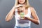 Beautiful young woman showing bottle of pills over gray background.