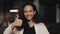 Beautiful young woman shows Thumbs Up and smiling standing in cozy cafe. Thumbs Up Sign by Young Girl At Work