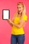 Beautiful young woman sin yellow t shirt holds tablet and surfs internet over pink background