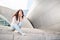 A beautiful young woman sits on the steps of the Walt Disney Concert Hall. Popular destination for sightseeing in Los Angeles