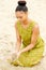 Beautiful young woman sitting at the beach with sand flowing from hands