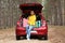 Beautiful young woman sitting in car trunk loaded with suitcases