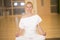 Beautiful young woman sitting in Lotos pose and practicing meditation in yoga hall