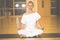 Beautiful young woman sitting in Lotos pose and practicing meditation in yoga hall