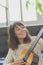 Beautiful young woman sitting on sofa playing guitar