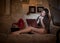 Beautiful young woman sitting on sofa working on laptop having a red gramophone near her, in boudoir scenery. Attractive brunette