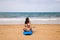 Beautiful young woman sitting on the surfboard on the shore of the beach. The woman is enjoying her trip to a paradise beach.