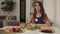 Beautiful young woman sitting on table with appetizing tasty breakfast medium shot