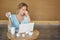 Beautiful young woman sitting on workplace with the laptop and tired crumpling the sheet