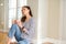 Beautiful young woman smiling confident and thinking positive sitting on the floor drinking coffee at home in the morning