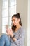 Beautiful young woman smiling confident and thinking positive sitting on the floor drinking coffee at home in the morning