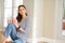 Beautiful young woman smiling confident and thinking positive sitting on the floor drinking coffee at home in the morning