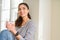 Beautiful young woman smiling confident and thinking positive sitting on the floor drinking coffee at home in the morning