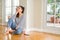 Beautiful young woman smiling confident and thinking positive sitting on the floor at home in the morning