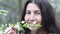 Beautiful young woman sniffing a flowering tree in the garden.