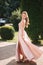 Beautiful young woman spin arround in gorgeous evening dress, background of green thee