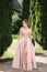 Beautiful young woman spin arround in gorgeous evening dress, background of green thee