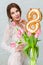 Beautiful young woman with spring tulips flowers bouquet. Happy girl smiling holds flowers, pink tulip. Spring portrait