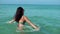 Beautiful young woman standing in clear sea water. Girl smiling, having great time on vacation. Magnificent background