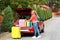 Beautiful young woman standing near car trunk loaded