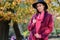 Beautiful young woman in stylish bright outfit walking in autumn park.