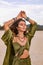 Beautiful young woman in stylish costume on the beach at sunset