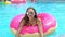 Beautiful young woman in summer. Bikini girl havin fun in in sprinkled donut float at pool, vacation, summer party
