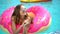 Beautiful young woman in summer. Bikini girl relaxing in in sprinkled donut float at pool, vacation, summer party, hotel