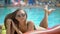 Beautiful young woman in summer. Bikini girl relaxing in tropical swimming pool. Girl sitting outdoors on summer day
