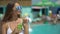 Beautiful young woman in summer. Bikini girl relaxing in tropical swimming pool. Happy woman drinking exotic cocktail by