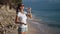 Beautiful young woman in sunglasses drinks clear water from bottle on beach