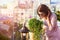 Beautiful young woman in sunglasses smelling the flowers in cafe