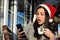 Beautiful young woman surprised using her cell phone while wearing a santa claus hat