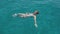 Beautiful young woman swims in clear blue water near Formentera or Ibiza islands around luxury yach. Slow motion