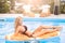 Beautiful young woman swims in the pool on inflatable toy in the form of a piece of fruit