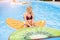 Beautiful young woman swims in the pool on inflatable toy in the form of a piece of fruit