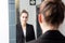 Beautiful young woman with tied hair in front of mirror