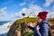 Beautiful young woman tourist at Cape Caba da Roca shoots the landscape on a mobile phone, winter trip to Portugal. Westernmost