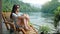 Beautiful young woman traveler resting in the mountains near the river