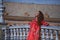 Beautiful young woman in a typical Moroccan red suit, embroidered with gold and silver threads, leaning on a tiled railing in the