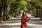 Beautiful young woman in a typical Moroccan red suit, embroidered with gold and silver threads, posing in an outdoor park avenue.