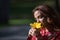 Beautiful young woman in a typical Moroccan red suit, embroidered with gold and silver threads, smelling a yellow pacific flower.