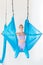 Beautiful young woman in uniform trainer shows asana stretching aero fly yoga on blue hammock in white class